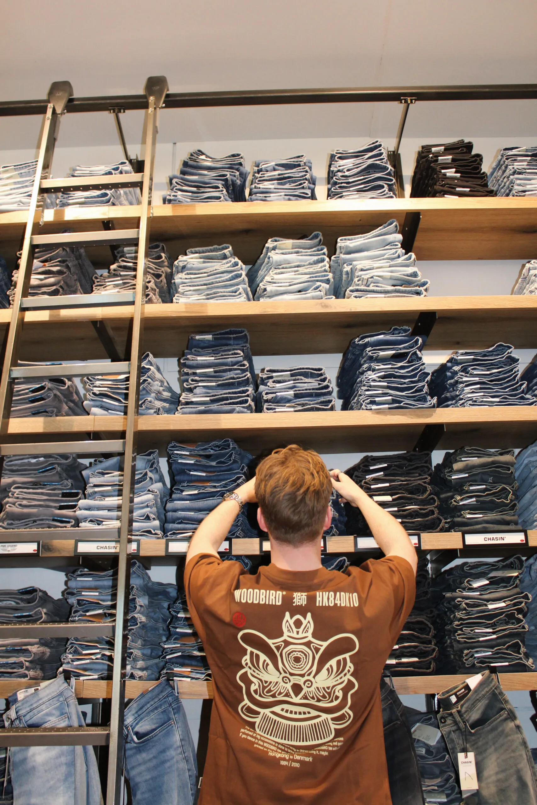 Denimwand in Score Groningen met klant voor de schappen.